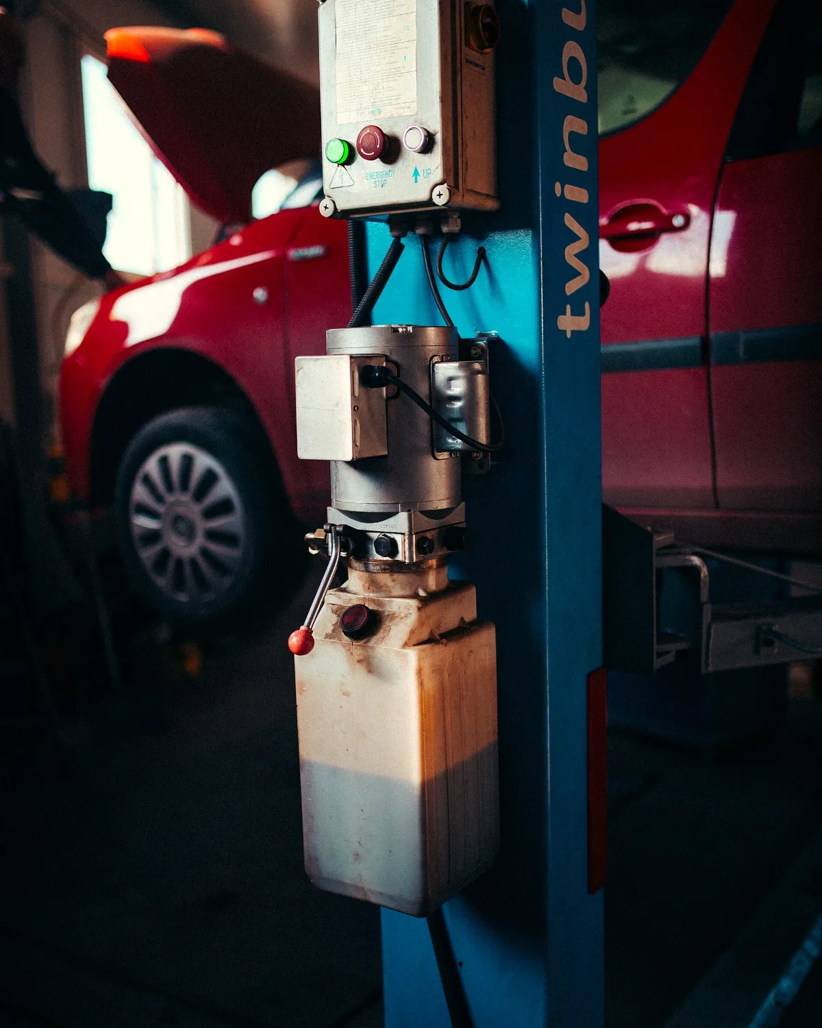 Coche rojo elevado en un taller (imagen de muestra)